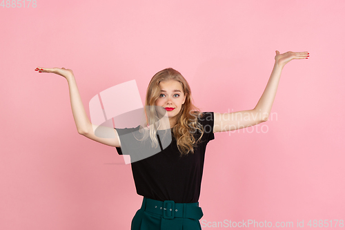 Image of Young emotional woman on pink studio background. Human emotions, facial expression concept.