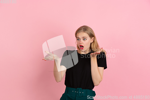 Image of Young emotional woman on pink studio background. Human emotions, facial expression concept.