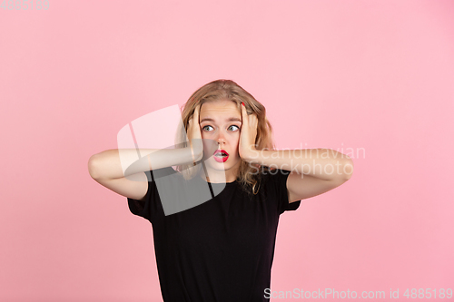 Image of Young emotional woman on pink studio background. Human emotions, facial expression concept.