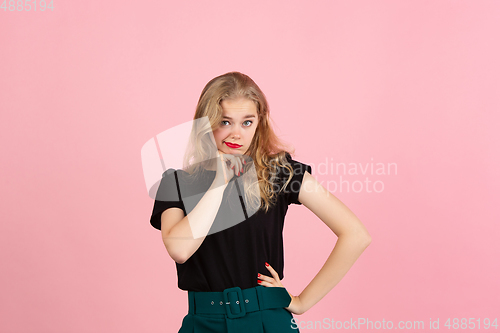 Image of Young emotional woman on pink studio background. Human emotions, facial expression concept.