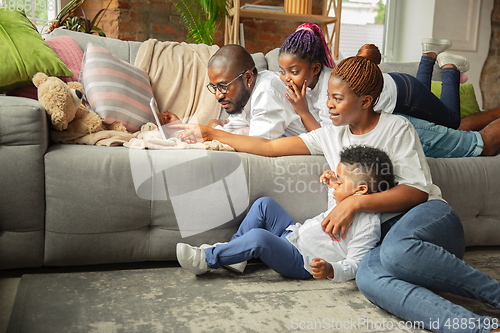 Image of Young african family during quarantine, insulation spending time together at home