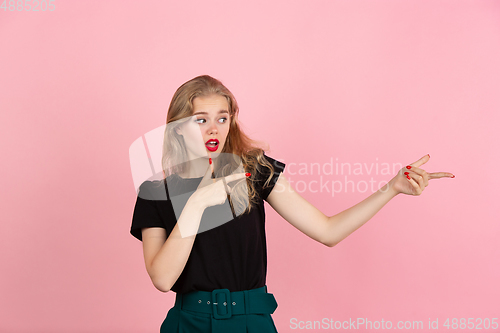 Image of Young emotional woman on pink studio background. Human emotions, facial expression concept.