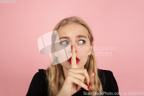 Image of Young emotional woman on pink studio background. Human emotions, facial expression concept.