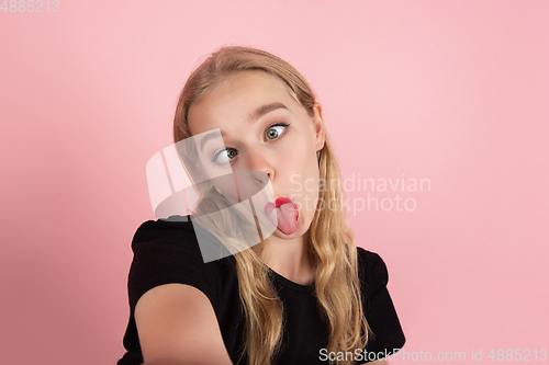Image of Young emotional woman on pink studio background. Human emotions, facial expression concept.