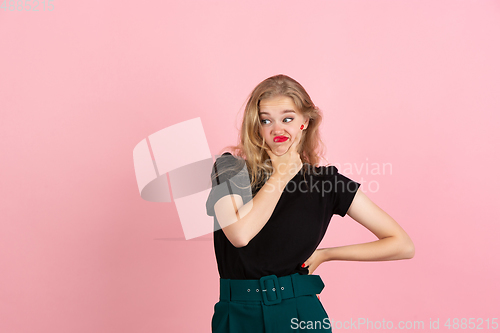 Image of Young emotional woman on pink studio background. Human emotions, facial expression concept.