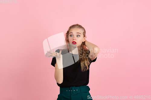 Image of Young emotional woman on pink studio background. Human emotions, facial expression concept.