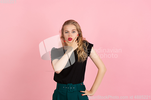 Image of Young emotional woman on pink studio background. Human emotions, facial expression concept.
