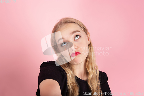 Image of Young emotional woman on pink studio background. Human emotions, facial expression concept.