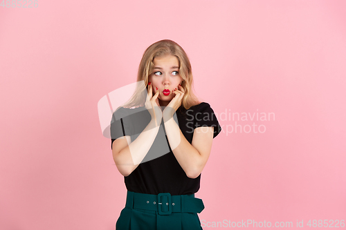 Image of Young emotional woman on pink studio background. Human emotions, facial expression concept.