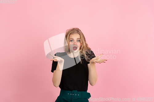 Image of Young emotional woman on pink studio background. Human emotions, facial expression concept.