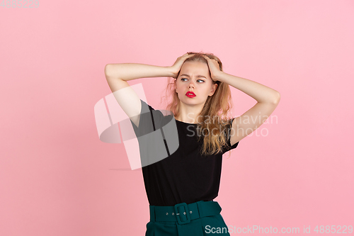 Image of Young emotional woman on pink studio background. Human emotions, facial expression concept.