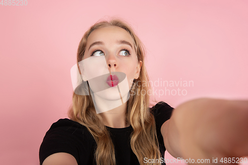 Image of Young emotional woman on pink studio background. Human emotions, facial expression concept.