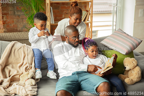 Image of Young african family during quarantine, insulation spending time together at home