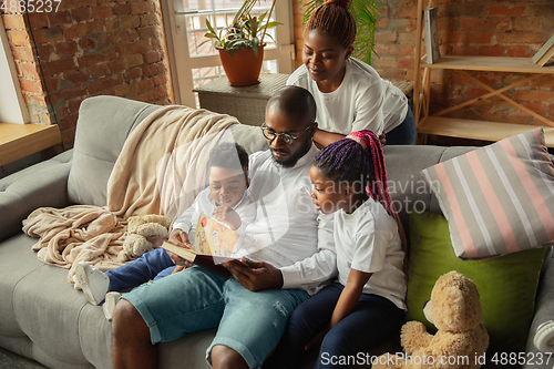 Image of Young african family during quarantine, insulation spending time together at home