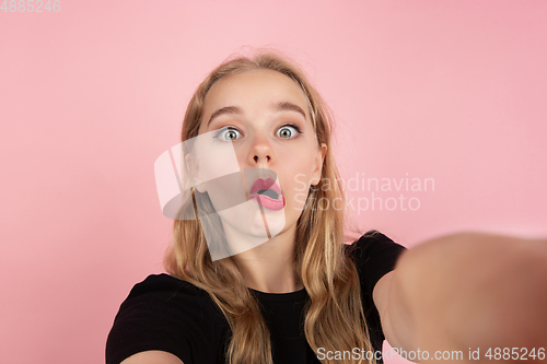 Image of Young emotional woman on pink studio background. Human emotions, facial expression concept.