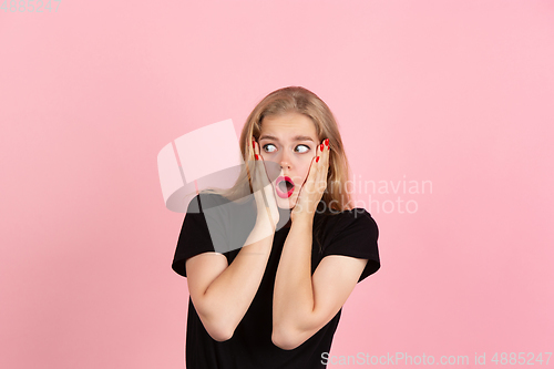 Image of Young emotional woman on pink studio background. Human emotions, facial expression concept.