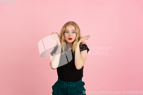 Image of Young emotional woman on pink studio background. Human emotions, facial expression concept.