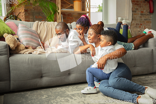 Image of Young african family during quarantine, insulation spending time together at home