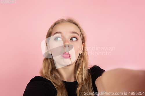 Image of Young emotional woman on pink studio background. Human emotions, facial expression concept.