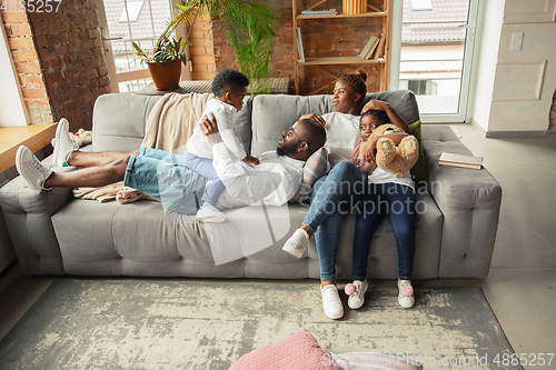 Image of Young african family during quarantine, insulation spending time together at home