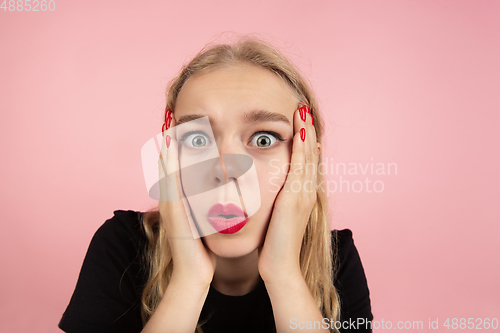 Image of Young emotional woman on pink studio background. Human emotions, facial expression concept.