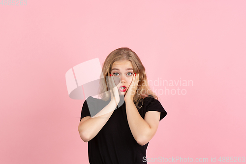 Image of Young emotional woman on pink studio background. Human emotions, facial expression concept.