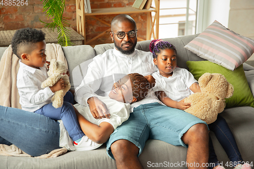 Image of Young african family during quarantine, insulation spending time together at home