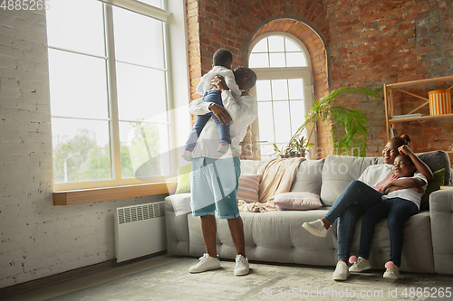 Image of Young african family during quarantine, insulation spending time together at home