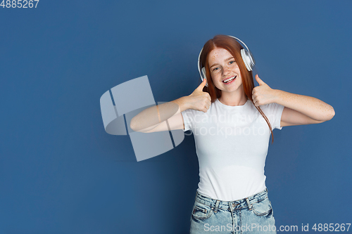 Image of Caucasian young girl\'s portrait isolated on blue studio background. Beautiful female model. Concept of human emotions, facial expression, sales, ad, youth culture.