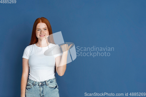 Image of Caucasian young girl\'s portrait isolated on blue studio background. Beautiful female model. Concept of human emotions, facial expression, sales, ad, youth culture.