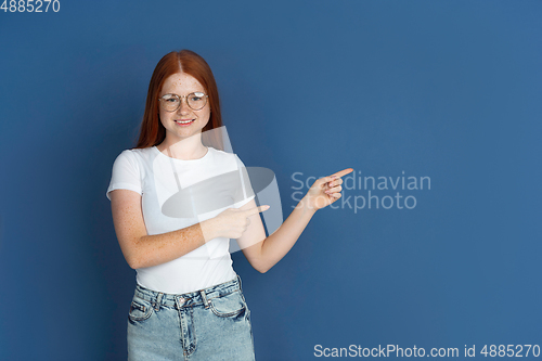 Image of Caucasian young girl\'s portrait isolated on blue studio background. Beautiful female model. Concept of human emotions, facial expression, sales, ad, youth culture.