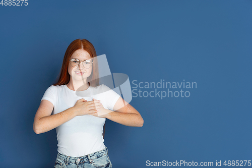 Image of Caucasian young girl\'s portrait isolated on blue studio background. Beautiful female model. Concept of human emotions, facial expression, sales, ad, youth culture.