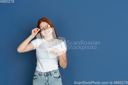 Image of Caucasian young girl\'s portrait isolated on blue studio background. Beautiful female model. Concept of human emotions, facial expression, sales, ad, youth culture.