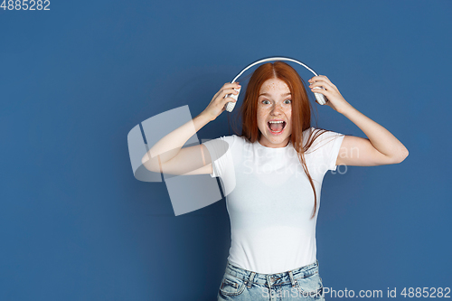 Image of Caucasian young girl\'s portrait isolated on blue studio background. Beautiful female model. Concept of human emotions, facial expression, sales, ad, youth culture.