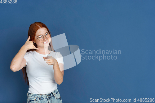 Image of Caucasian young girl\'s portrait isolated on blue studio background. Beautiful female model. Concept of human emotions, facial expression, sales, ad, youth culture.