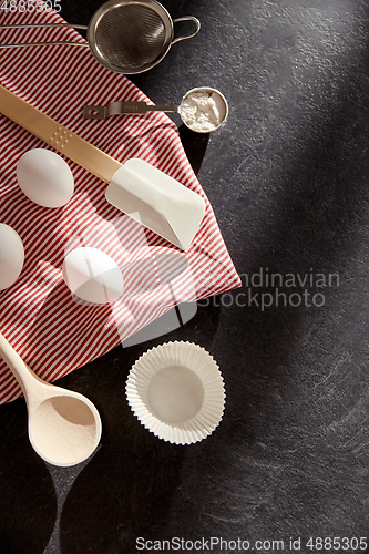 Image of eggs, flour, spoon, spatula, strainer and towel