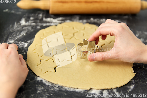 Image of hands cutting dough with star mold on table