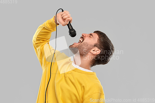 Image of man in yellow sweatshirt with microphone singing