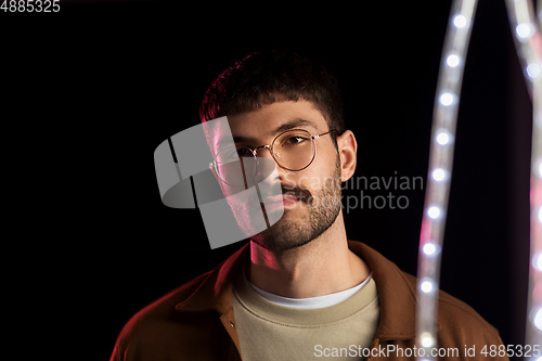 Image of man in glasses over neon lights at nightclub