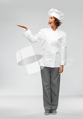 Image of smiling female chef holding something on hand