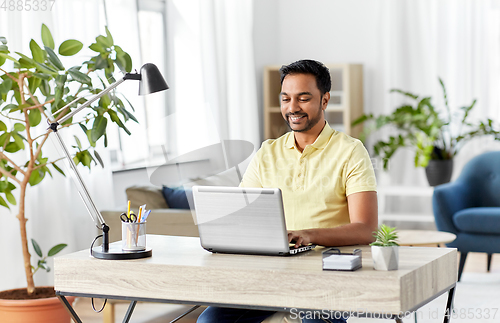 Image of indian man with laptop working at home office