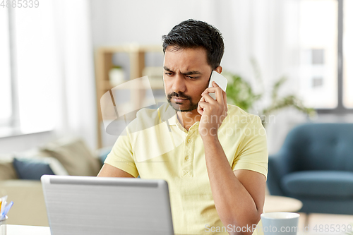 Image of man calling on smartphone at home office