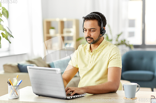 Image of indian man with headset and laptop working at home