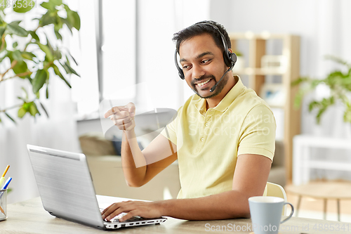 Image of indian man with headset and laptop working at home