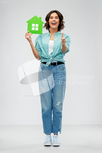 Image of smiling young woman holding green house