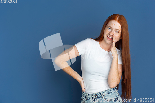 Image of Caucasian young girl\'s portrait isolated on blue studio background. Beautiful female model. Concept of human emotions, facial expression, sales, ad, youth culture.