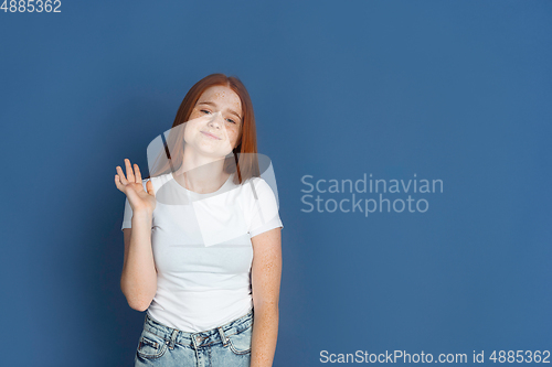 Image of Caucasian young girl\'s portrait isolated on blue studio background. Beautiful female model. Concept of human emotions, facial expression, sales, ad, youth culture.