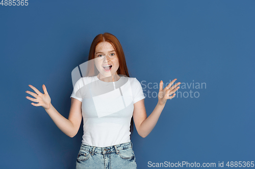 Image of Caucasian young girl\'s portrait isolated on blue studio background. Beautiful female model. Concept of human emotions, facial expression, sales, ad, youth culture.