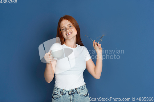 Image of Caucasian young girl\'s portrait isolated on blue studio background. Beautiful female model. Concept of human emotions, facial expression, sales, ad, youth culture.