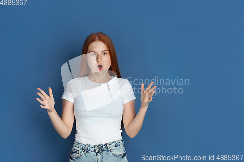 Image of Caucasian young girl\'s portrait isolated on blue studio background. Beautiful female model. Concept of human emotions, facial expression, sales, ad, youth culture.